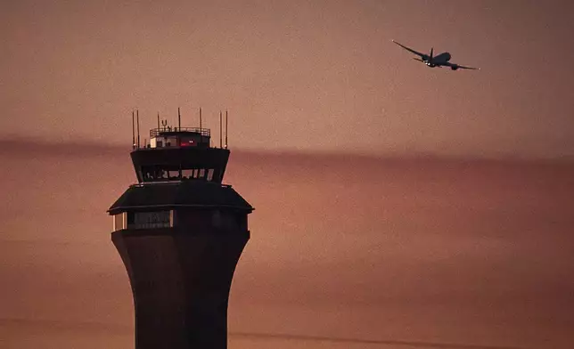 A plane flies by a control tower at Newark Liberty International Airport on Friday, Nov. 7, 2025, in Newark, N.J. (AP Photo/Andres Kudacki)