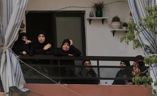 Hezbollah supporters mourn as they stand at their apartment balcony watching the funeral procession of Hezbollah's chief of staff, Haytham Tabtabai, and other fighters who were killed in Sunday's Israeli airstrike, in the southern suburb of Beirut, Lebanon, Monday, Nov. 24, 2025. (AP Photo/Hussein Malla)