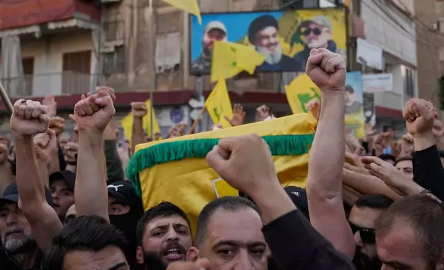Hezbollah supporters shout slogans and raise their hands, as they carry the coffins of Hezbollah's chief of staff, Haytham Tabtabai, who was killed with other two Hezbollah fighters in Sunday's Israeli airstrike during their funeral procession, in the southern suburb of Beirut, Lebanon, Monday, Nov. 24, 2025. (AP Photo/Hussein Malla)