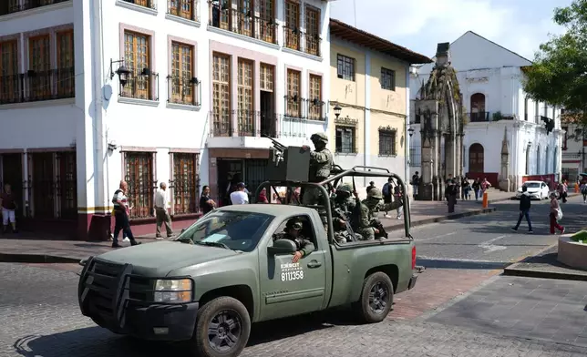 Soldiers patrol Uruapan, Mexico, Friday, Nov. 21, 2025, as Michoacan state prosecutor officers detain a suspect in the killing of the city's Mayor Carlos Manzo Rodriguez. (AP Photo/Eduardo Verdugo)