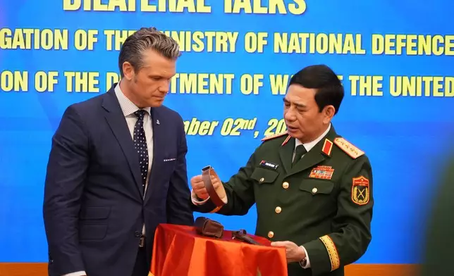 Vietnamese Defense Minister Phan Van Giang holds up a belt during an artifact exchange with U.S. Defense Secretary Pete Hegseth after their meetingin Hanoi, Vietnam, Sunday, Nov. 2, 2025. (AP Photo/Hau Dinh)