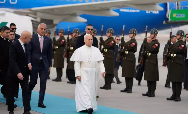 Pope Leo XIV walks as he is welcomed upon his arrival at Esenboga International Airport in Ankara, Turkey, Thursday, Nov. 27, 2025, marking the beginning of his first foreign trip. (AP Photo/Khalil Hamra)