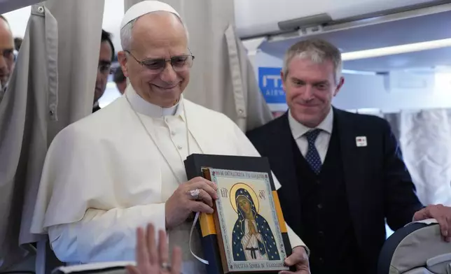 Pope Leo XIV greets reporters aboard a flight on his way to Ankara, Turkey, for a six-day trip to Turkey and Lebanon, Thursday, Nov. 27, 2025. (AP Photo/Domenico Stinellis, Pool)