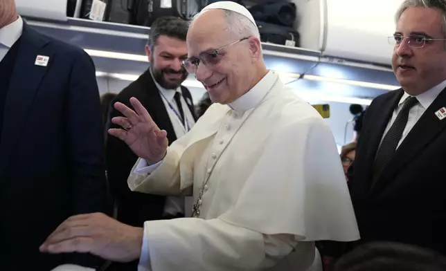 Pope Leo XIV greets reporters aboard a flight on his way to Ankara, Turkey, for a six-day trip to Turkey and Lebanon, Thursday, Nov. 27, 2025. (AP Photo/Domenico Stinellis, Pool)