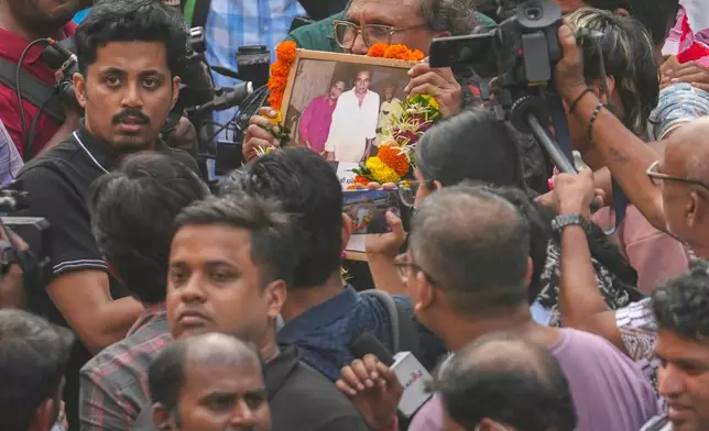A fan holds the photograph of Bollywood actor Dharmendra during his funeral outside a cremation center in Mumbai India, Monday, Nov. 24, 2025.(AP Photo/Rafiq Maqbool)