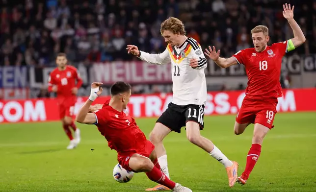 Germany's Nick Woltemade, center, fights for the ball with Luxembourg's Laurent Jans, right, during the 2026 World Cup group A qualifying soccer match between Luxembourg and Germany in Luxembourg, Friday, Nov. 14, 2025. (AP Photo/Geert Vanden Wijngaert)
