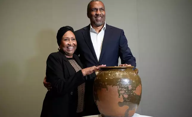 Pauline Baker and her son, Yaba Baker, pose with one of the pots created by their enslaved ancestor, David Drake, at the Museum of Fine Arts, Monday, Nov. 10, 2025, in Boston. (AP Photo/Robert F. Bukaty)