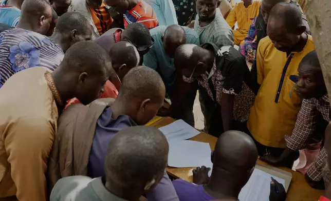 Parents give their children's information to authorities outside the St. Mary's Catholic Primary and Secondary School in Papiri community, Nigeria, Friday, Nov. 28, 2025. (AP Photo )