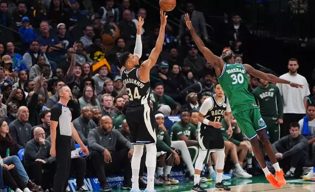 Milwaukee Bucks forward Giannis Antetokounmpo (34) shoots a three-pointer against Dallas Mavericks center Moussa Cisse (30) during the second half of an NBA basketball game in Dallas, Monday, Nov. 10, 2025. (AP Photo/LM Otero)