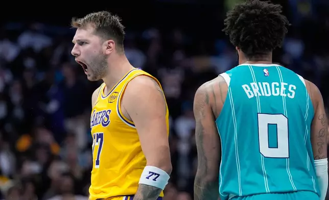 Los Angeles Lakers guard Luka Doncic celebrates after scoring as Charlotte Hornets forward Miles Bridges looks on during the second half of an NBA basketball game Monday, Nov. 10, 2025, in Charlotte, N.C. (AP Photo/Chris Carlson)