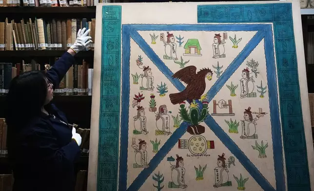 Rosalba Sanchez Flores, a historian at the National Museum of Anthropology in Mexico City, points to the details of Mexico's coat of arms as depicted in the Codex Mendoza, Friday, Nov. 14, 2025. (AP Photo/Claudia Rosel)
