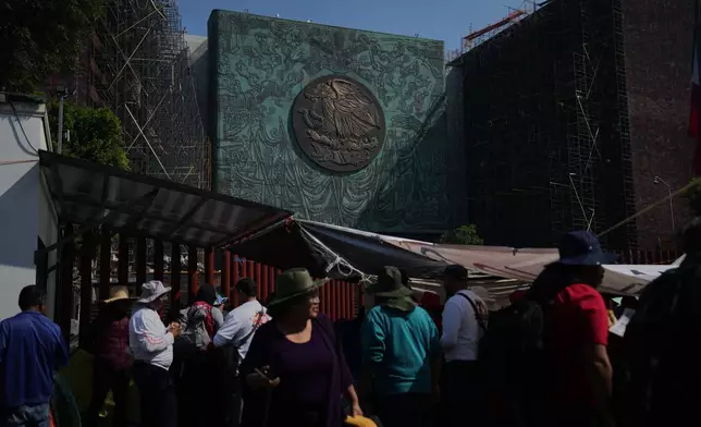 Protesters gather in front of the Legislative Palace of San Lazaro in Mexico City, where the Mexican coat of arms is visible on the building's façade, Thursday, Nov. 13, 2025. (AP Photo/Claudia Rosel)