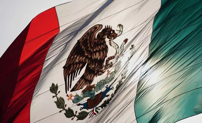 Mexico's coat of arms decorates a large flag in the city's Zocalo square, Mexico City, Thursday, Nov. 13, 2025. (AP Photo/Claudia Rosel)