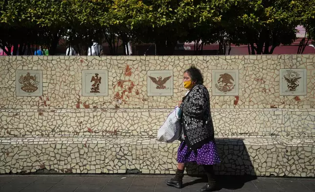 People sit on benches in Plaza del Aguilita, where the evolution of the Mexican coat of arms is showcased, Mexico City, Thursday, Nov. 13, 2025. (AP Photo/Claudia Rosel)