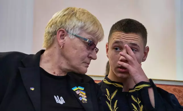 Liudmyla Siryk, left, listens to her grandson, Oleksandr Radchuk, during a press conference on the return of Ukrainian children and civilians taken by Russia during the three-and-a-half-year war, at the Embassy of Ukraine in Italy, in Rome, Wednesday, Nov. 19, 2025. (AP Photo/Domenico Stinellis)