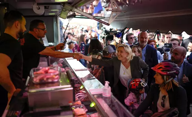 FILE - French far-right leader Marine Le Pen, center, greets people as she campaigns in a market in Pertuis, southern France, Friday, April 15, 2022. (AP Photo/Daniel Cole, File)