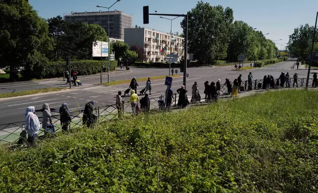 FILE - Residents line up during a distribution to collect soap, vegetables, fruits and other staples distributed by volunteers from community organizations of ACLEFEU in Clichy-sous-Bois, north suburb of Paris, Wednesday, April 22, 2020 as a nationwide confinement continues to counter the COVID-19. (AP Photo/Francois Mori, File)