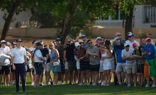 Spectators watch as Justin Rose of England plays his second shot on the 1st hole during the third round of World Tour Golf Championship at Jumeirah Golf Estates, in Dubai, United Arab Emirates, Saturday, Nov. 15, 2025. (AP Photo/Altaf Qadri)
