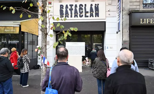 People pay their respects to victims in front of the Bataclan concert hall as Paris is marking the 10th anniversary of terrorist attacks that killed 132 people and injured hundreds, Thursday, Nov. 13, 2025 in Paris. (AP Photo/Emma Da Silva)