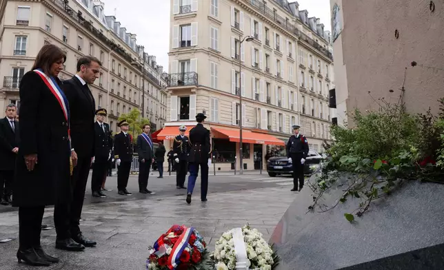 Paris mayor Anne Hidalgo and French President Emmanuel Macron pay tribute to victims near "Le Petit Cambodge" and "Le Carillon" cafes, Thursday Nov. 13, 2025 in Paris during ceremonies marking the 10th anniversary of terrorist attacks that killed 132 people and injured hundreds. (Ludovic Marin, Pool photo via AP)