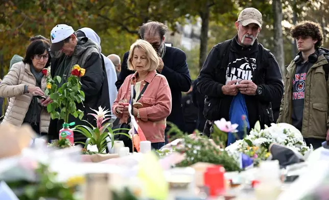 People watch flowers laid at the statue of the Place de la Republique (Republic Square) as Paris is marking the 10th anniversary of terrorist attacks that killed 132 people and injured hundreds, Thursday, Nov. 13, 2025 in Paris. (AP Photo/Emma Da Silva)