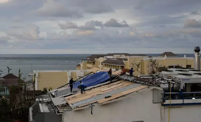 People repair the roof of a resort in Montego Bay, Jamaica, Friday, Oct. 31, 2025, in the aftermath of Hurricane Melissa. (AP Photo/Matias Delacroix)