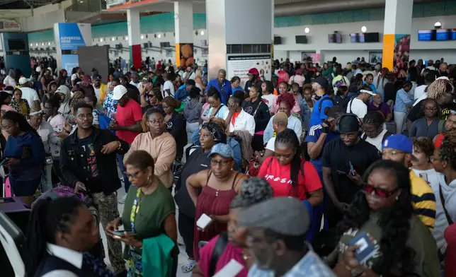 Passengers check in at the Norman Manley International Airport in Kingston, Jamaica, Saturday, Nov. 1, 2025, in the aftermath of Hurricane Melissa. (AP Photo/Matias Delacroix)