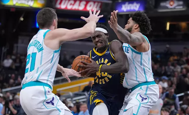 Indiana Pacers forward Pascal Siakam (43) drives between Charlotte Hornets guard Pat Connaughton (21) and forward Miles Bridges (0) during the second half of an NBA basketball game in Indianapolis, Wednesday, Nov. 19, 2025. (AP Photo/Michael Conroy)