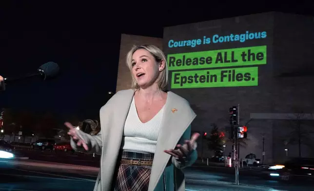 Danielle Bensky talks to reporters as a World Without Exploitation projection is seen on the wall of the National Gallery of Art calling on Congress to vote yes on the Epstein files transparency act in Washington, Monday, Nov. 17, 2025. (AP Photo/Jose Luis Magana)