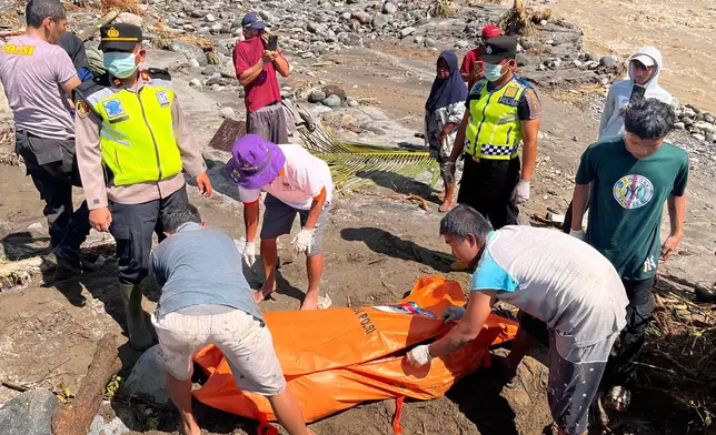 Rescuers put the body of a flood victim recovered from a river inside a body bag in Padang Pariaman, West Sumatra, Indonesia, Saturday, Nov. 29, 2025. (AP Photo/Ade Yuandha)