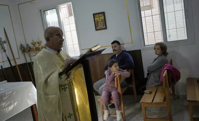 Priest Maurice El Khoury, left, leads Sunday Mass inside a room usually used as a residence for visiting bishops next to St. George Melkite Catholic Church, which was destroyed in an Israeli airstrike, in the town of Dardghaya, southern Lebanon, Sunday, Nov. 16, 2025. (AP Photo/Hassan Ammar)