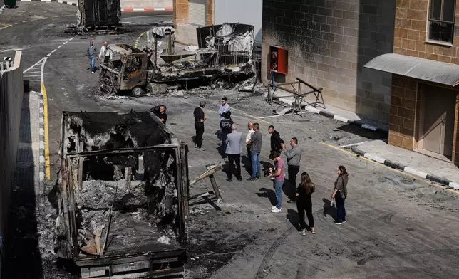 Palestinians and journalists survey damage in an industrial zone following an attack by Israeli settlers the previous day in the West Bank village of Beit Lid, near Tulkarm, Wednesday, Nov. 12, 2025. (AP Photo/Majdi Mohammed)