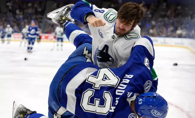 Vancouver Canucks right wing Conor Garland (8) knocks down Tampa Bay Lightning defenseman Darren Raddysh (43) as they fight during the first period of an NHL hockey game Sunday, Nov. 16, 2025, in Tampa, Fla. (AP Photo/Chris O'Meara)