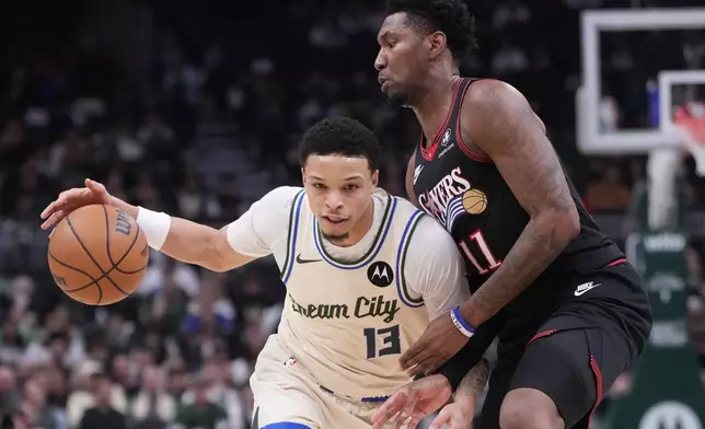 Milwaukee Bucks' Ryan Rollins tries to get past Philadelphia 76ers' Justin Edwards during the first half of an NBA basketball game Thursday, Nov. 20, 2025, in Milwaukee. (AP Photo/Morry Gash)
