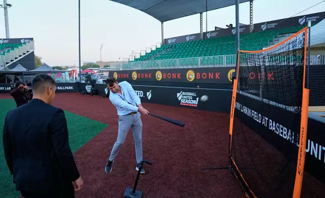 A journalist takes a swing after a press presentation ahead of the league's inaugural season at the new Barry Larkin Field in Ud al-Bayda, on the outskirts of Dubai, United Arab Emirates, Thursday, Nov. 13, 2025. (AP Photo/Fatima Shbair)