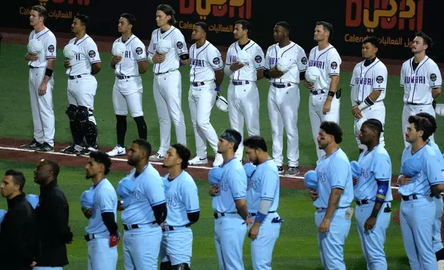 Players from the Mumbai and Karachi teams line up ahead of the league's opening baseball game at the new Barry Larkin Field in Ud al-Bayda, on the outskirts of Dubai, United Arab Emirates, Friday, Nov. 14, 2025. (AP Photo/Fatima Shbair)
