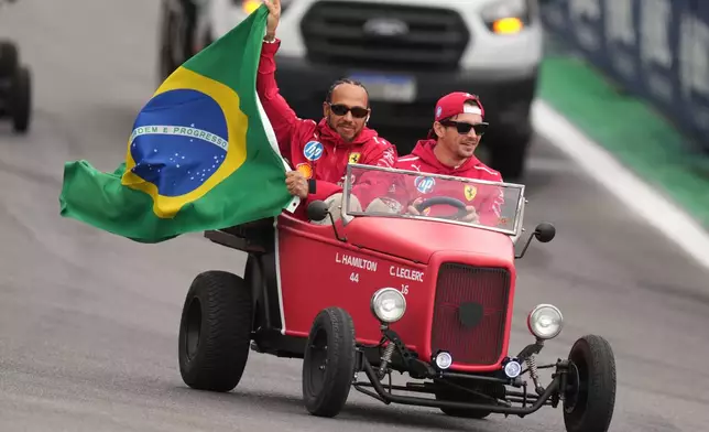 Ferrari driver Lewis Hamilton of Britain, left, and Ferrari driver Charles Leclerc of Monaco wave to the crowd during the opening parade at the Brazilian Formula One Grand Prix at the Interlagos race track in Sao Paulo, Sunday, Nov. 9, 2025. (AP Photo/Andre Penner)