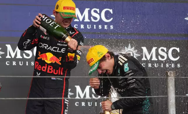 Red Bull driver Max Verstappen of the Netherlands, left, sprays champagne on Mercedes driver Kimi Antonelli of Italy at the podium during the Brazilian Formula One Grand Prix at the Interlagos race track in Sao Paulo, Sunday, Nov. 9, 2025. (AP Photo/Andre Penner)