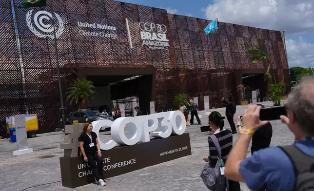 People take pictures outside the venue for the COP30 U.N. Climate Summit, Thursday, Nov. 20, 2025, in Belem, Brazil. (AP Photo/Joshua A. Bickel)