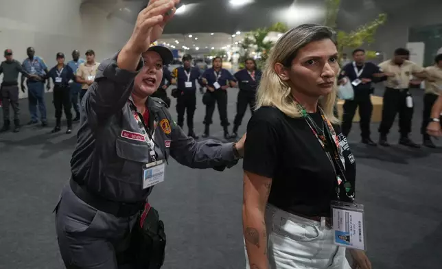 Security officials direct attendees to leave the venue for the COP30 U.N. Climate Summit, Thursday, Nov. 20, 2025, in Belem, Brazil. (AP Photo/Andre Penner)