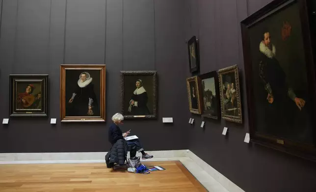 A woman draws in the Richelieu gallery of Le Louvre museum are seen Wednesday, Nov. 19, 2025 in Paris. (AP Photo/Christophe Ena)