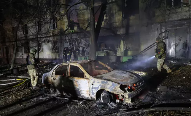 Rescue workers try to put out a fire of a residential building burning after a Russian attack on Zaporizhzhia, Ukraine, Wednesday, Nov. 26, 2025. (AP Photo/Kateryna Klochko)