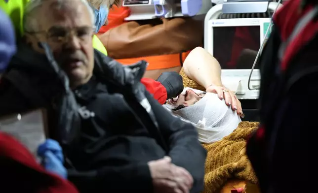 Paramedics treat people who were injured after a Russian attack on a residential neighborhood in Zaporizhzhia, Ukraine, Wednesday, Nov. 26, 2025. (AP Photo/Kateryna Klochko)