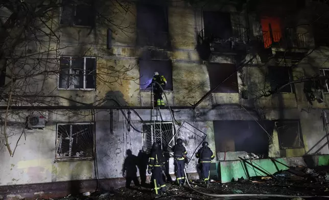 Rescue workers try to put out a fire of residential building burning after a Russian attack on Zaporizhzhia, Ukraine, Wednesday, Nov. 26, 2025. (AP Photo/Kateryna Klochko)