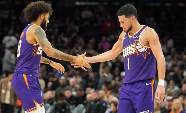 Phoenix Suns forward Isaiah Livers (18) slaps hands with Devin Booker (1) during the second half of an NBA basketball game against San Antonio Spurs in Phoenix, Sunday, Nov. 23, 2025. (AP Photo/Darryl Webb)