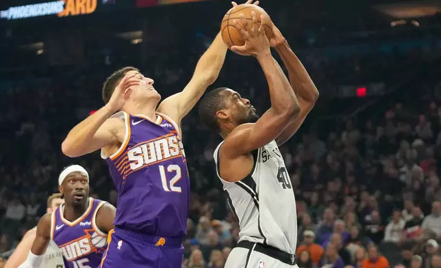 Phoenix Suns guard Collin Gillespie (12) goes for a block on San Antonio Spurs forward Harrison Barnes during the first half of an NBA basketball game in Phoenix, Sunday, Nov. 23, 2025. (AP Photo/Darryl Webb)
