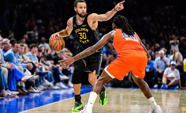 Golden State Warriors guard Stephen Curry (30) gestures against Oklahoma City Thunder guard Cason Wallace (22) during the first half of an NBA basketball game, Tuesday, Nov. 11, 2025, in Oklahoma City. (AP Photo/Gerald Leong)