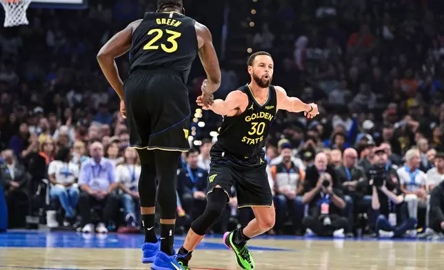 Golden State Warriors guard Stephen Curry (30) celebrates with Golden State Warriors forward Draymond Green (23) during the first half of an NBA basketball game, Tuesday, Nov. 11, 2025, in Oklahoma City. (AP Photo/Gerald Leong)