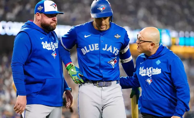 Toronto Blue Jays' George Springer, center, walks off the field as he leaves with an injury with manager John Schneider, left, and first assistant athletic trainer Voon Chong, right, during the seventh inning in Game 3 of baseball's World Series against the Los Angeles Dodgers in Los Angeles, Monday, Oct. 27, 2025. (Frank Gunn/The Canadian Press via AP)