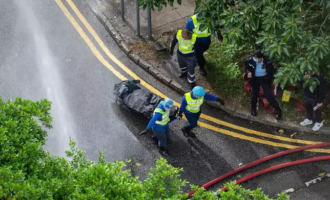 Workers remove a body from a fire which broke out Wednesday at Wang Fuk Court, a residential estate in the Tai Po district of Hong Kong's New Territories, Thursday, Nov. 27, 2025. (AP Photo/Chan Long Hei)